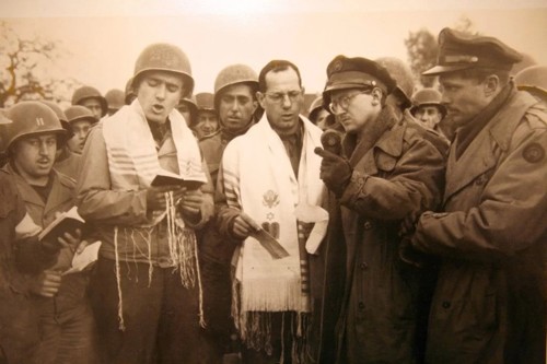 בזמן 'התפילה באַאכֶן' מול בית הכנסת החרב של אַאכֶן – סגן מקס פוקס (שני משמאל); כתב אֵן-בִּי-סִי ג'יימס קאסידי (שני מימין) (נחלת הכלל)