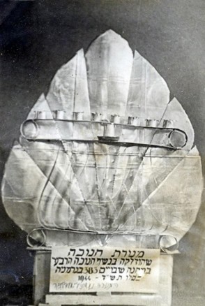 מנורת חנוכה שהכין אברהם דייגי בשנת 1944 במחנה שבויים בגרמניה. המנורה הוכנה משאריות של קופסאות שימורים שהגיעו בחבילות הצלב האדום. מתוך עיזבונו של קורפורל אברהם דייגי PAL/11020, פלוגה 602 של חיל החפרים הארץ-ישראלי – מפדויי השבי